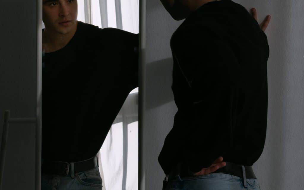 Se me abulta la cicatriz al ponerme de pie: qué es normal (y qué no) después de operarte la espalda 1 Hombre mirándose la espalda en el espejo después de una operación de columna